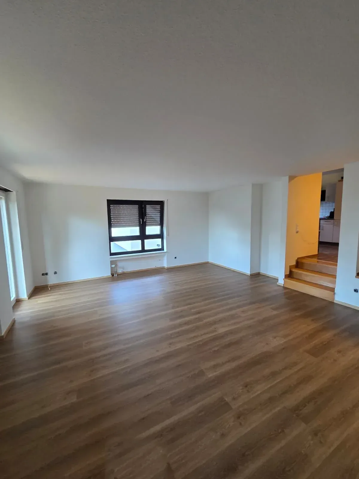 Renovierter Wohnraum mit neu verlegtem Boden und hellen Wänden